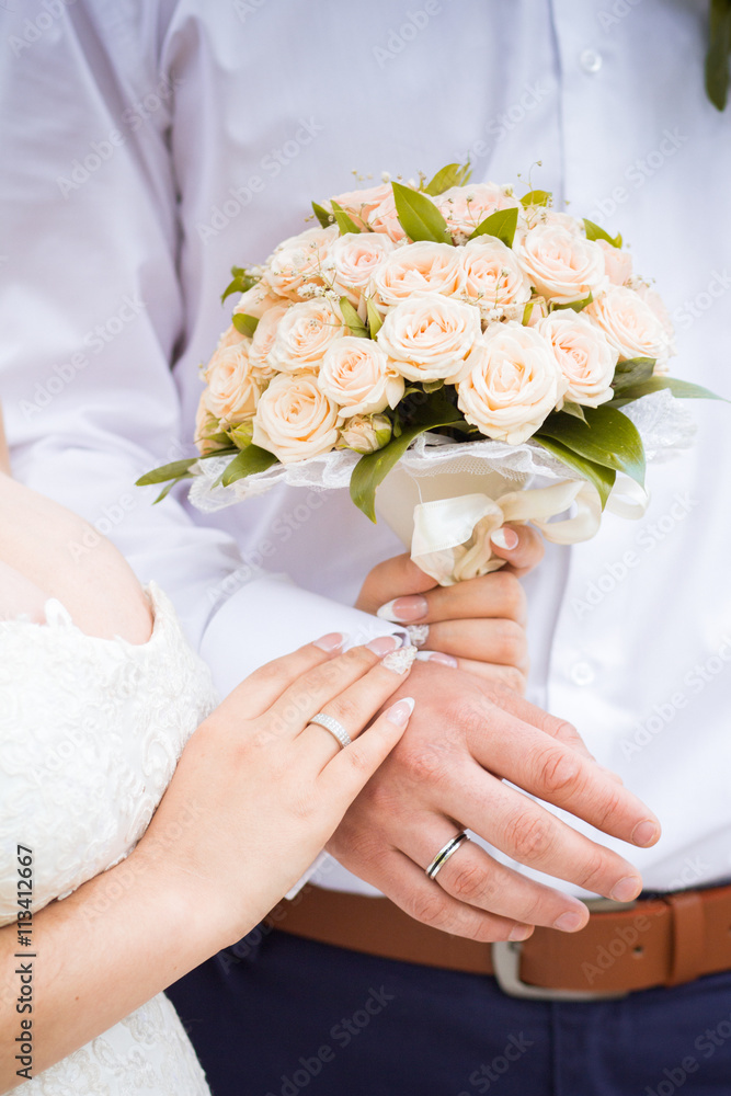wedding.hands of man and woman with wedding rings holding a bouquet of roses wedding.hands of man and woman with wedding rings holding a bouquet of roses