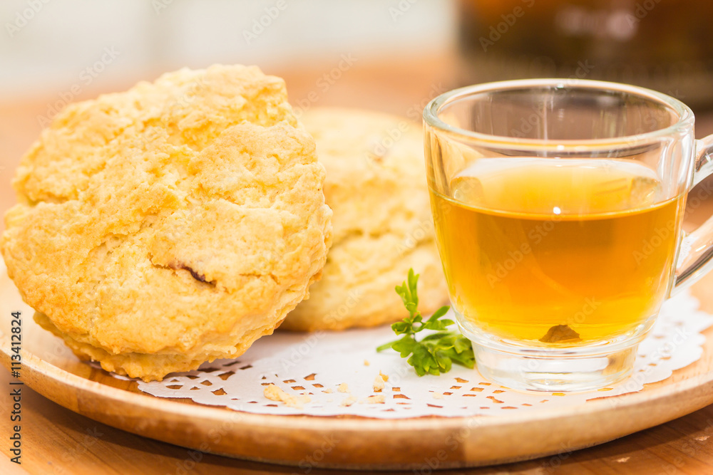 Place the scones on a plate, dessert and tea on wooden flooring. Place the scones on a plate, dessert and tea on wooden flooring.