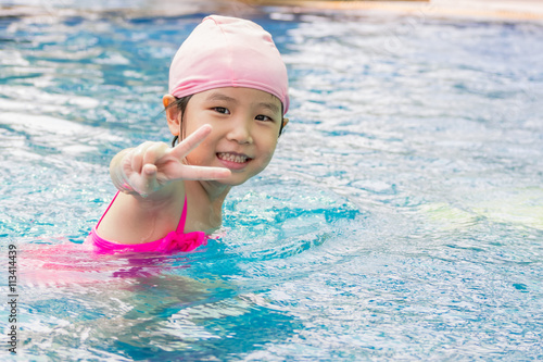 Asian girl is playing in the pool, victory fingers © bjginny