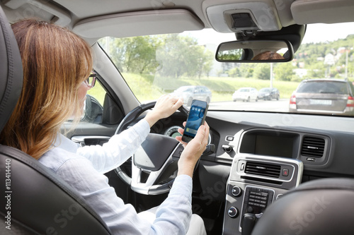 фотографія Dangerous driver. Woman using handy in her car while driving