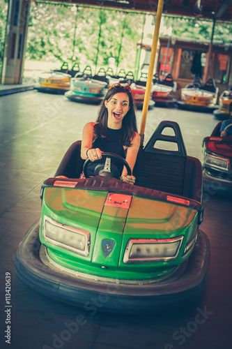 Cute young woman having fun in electric bumper car in amusement park © guruXOX