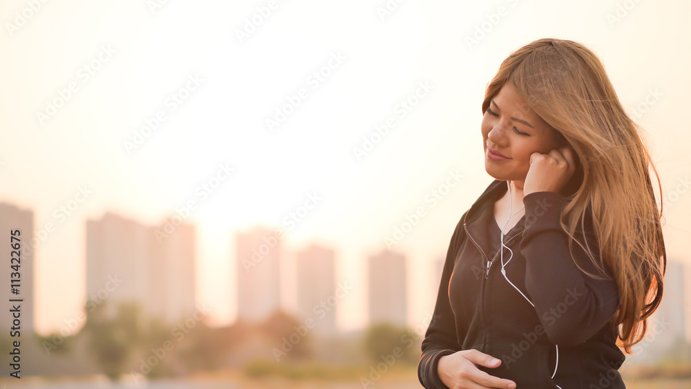 asian woman listening to music with sunset sky background