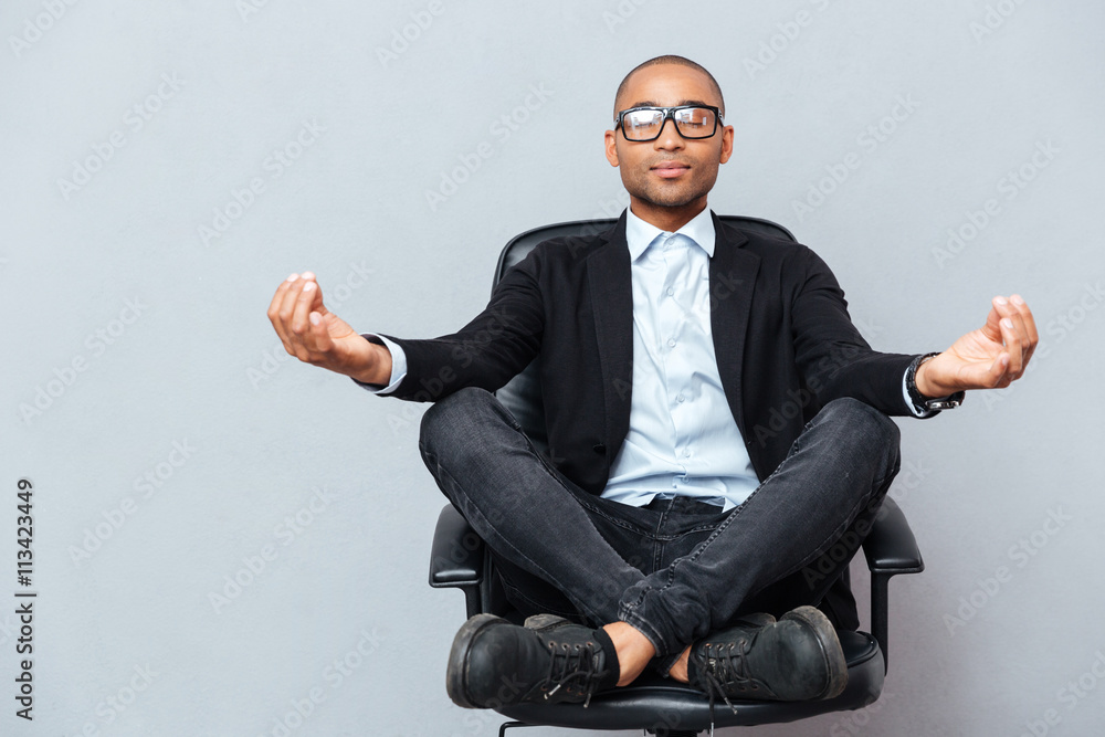 Attractive young man in glasses meditating on office chair - obrazy, fototapety, plakaty 