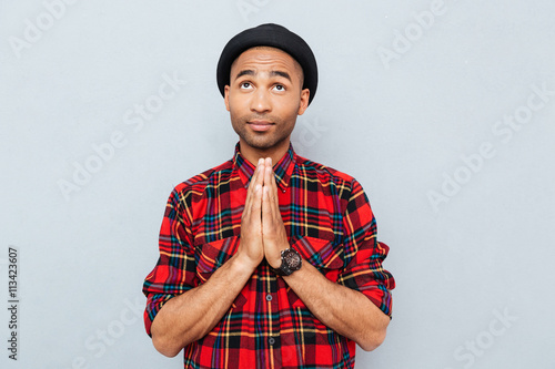Handsome african american man in black hat standing and praying