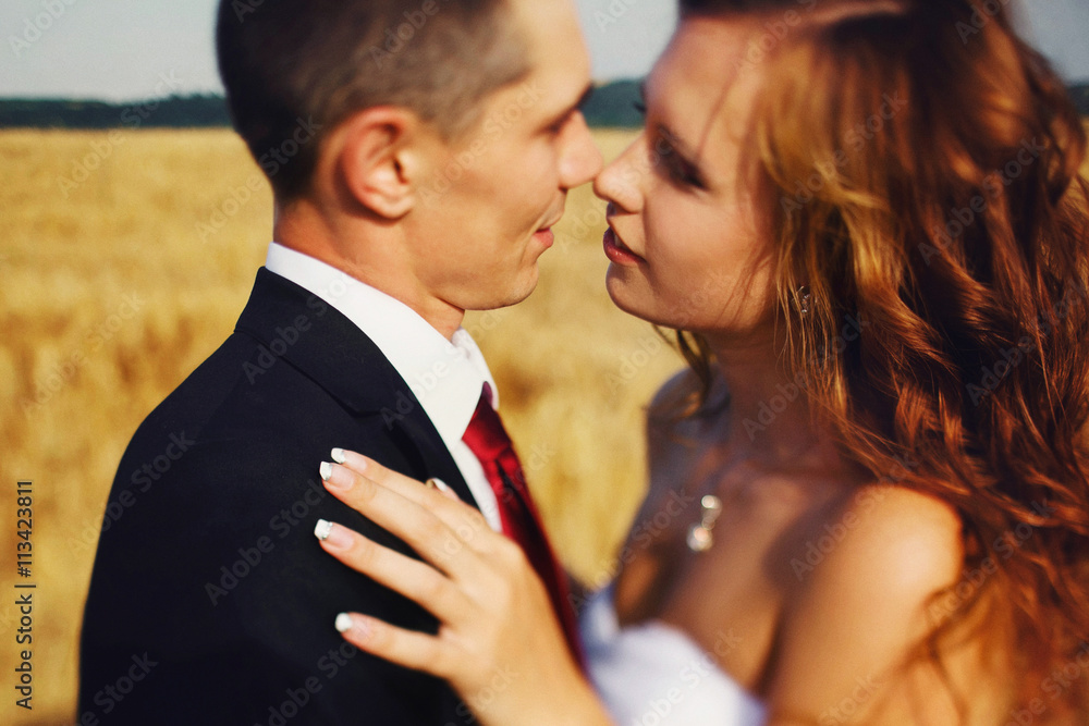 Bride reaches to kiss a fiance while wind blows her hair