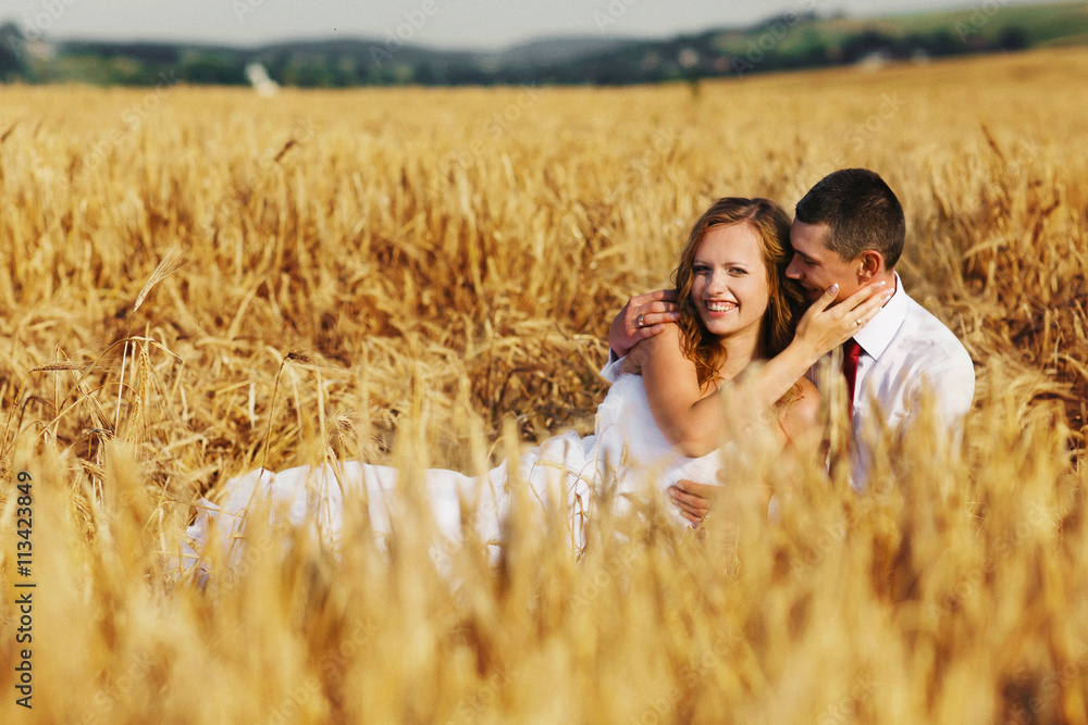 Bride and groom lie among the wheat on the field