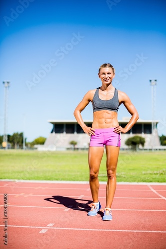 Female athlete standing with hand on hip on the running track