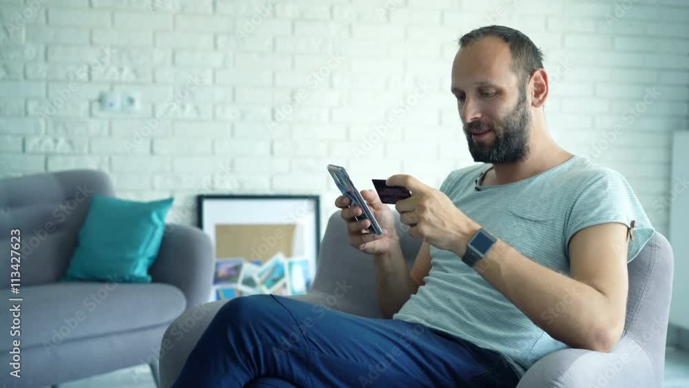 Man doing online shopping on smartphone at home
Man doing online shopping on smartphone at home