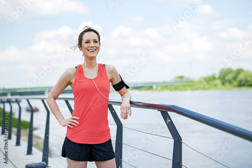 Fit woman jogger resting after run listening music. © Wisiel