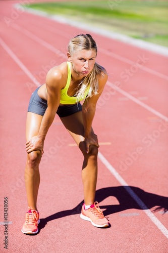 Tired female athlete standing on running track