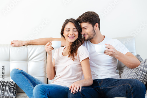 Portrait of a happy couple on the couch drinking coffee