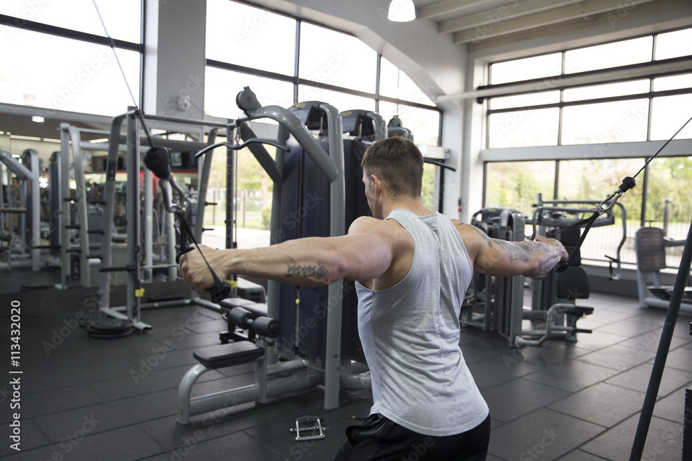Young Man Using Fitness Equipment In Gym Young Man Using Fitness Equipment In Gym