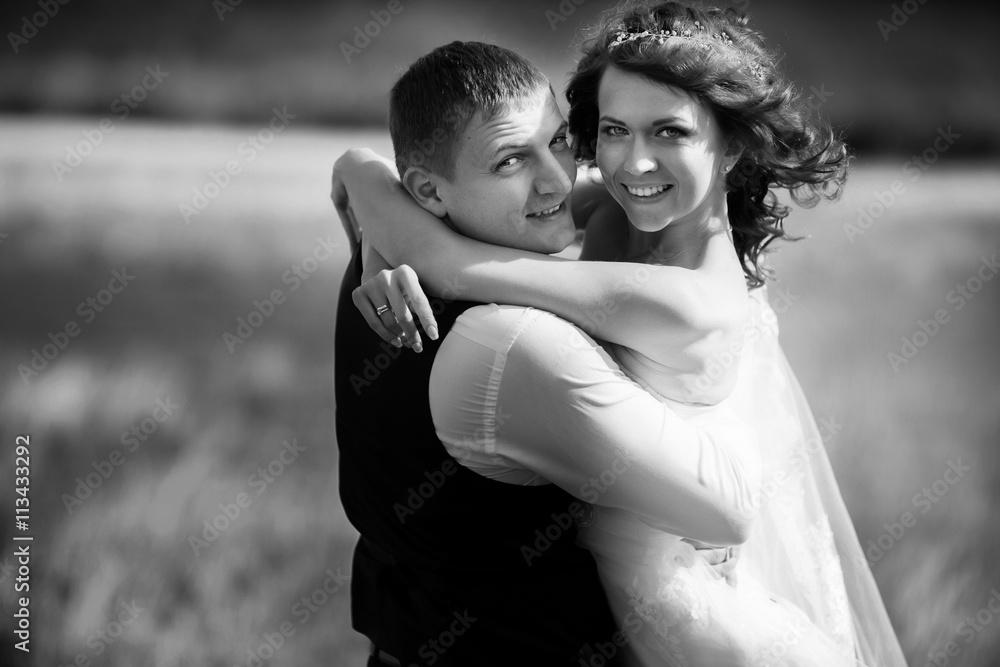 Bride ang groom look joyful hugging somewhere on the field Bride ang groom look joyful hugging somewhere on the field