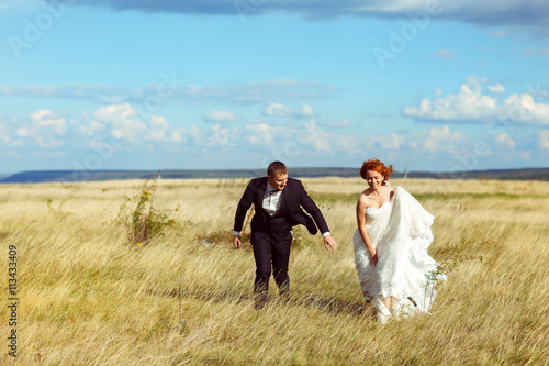 Bride walks across the field holding her dress in hands