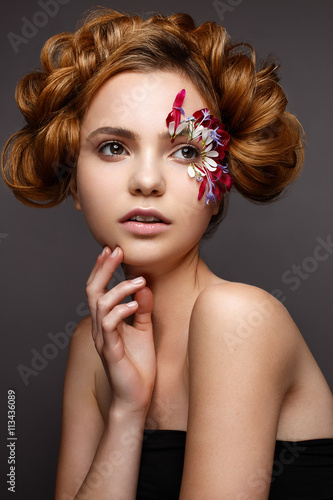 Beautiful girl with creative make-up with floral appliques. The model in the style of romantic with flower petals around her eyes. The photo was made in a studio. Beauty face