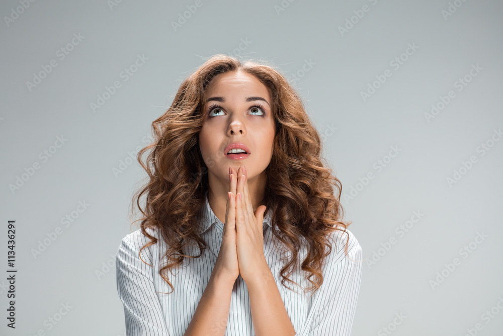 Woman is looking imploring over gray background Woman is looking imploring over gray background
