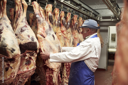 Butcher Working In Cold Store With Carcasses Of Meat