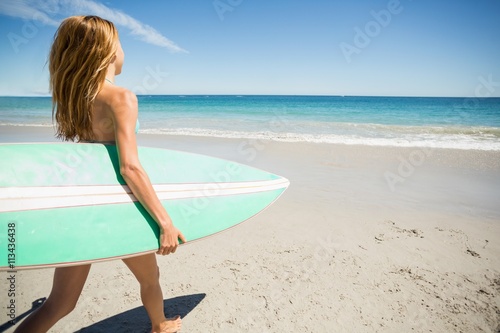 Woman walking with surfboard on beach