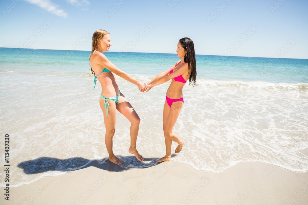 Female friends holding hands on beach