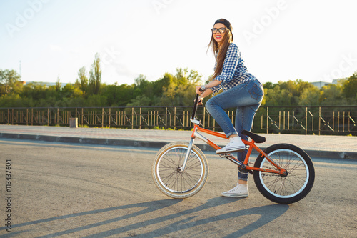Lovely young woman in a hat riding a bicycle on city background
