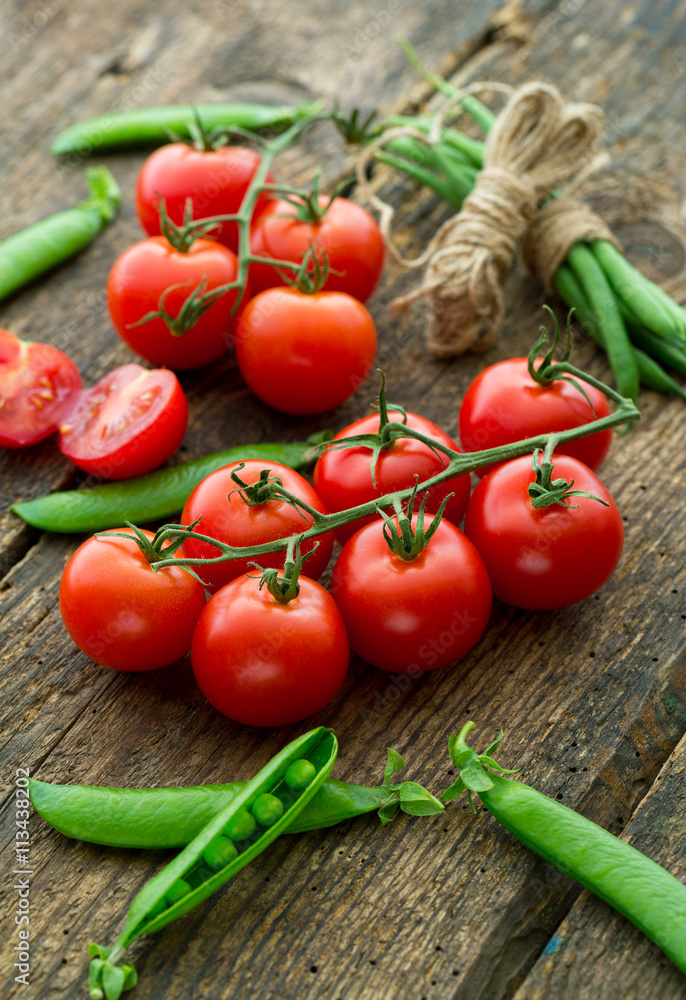 Fresh tomatoes with asparagus and green peas on a wooden backgro Fresh tomatoes with asparagus and green peas on a wooden backgro