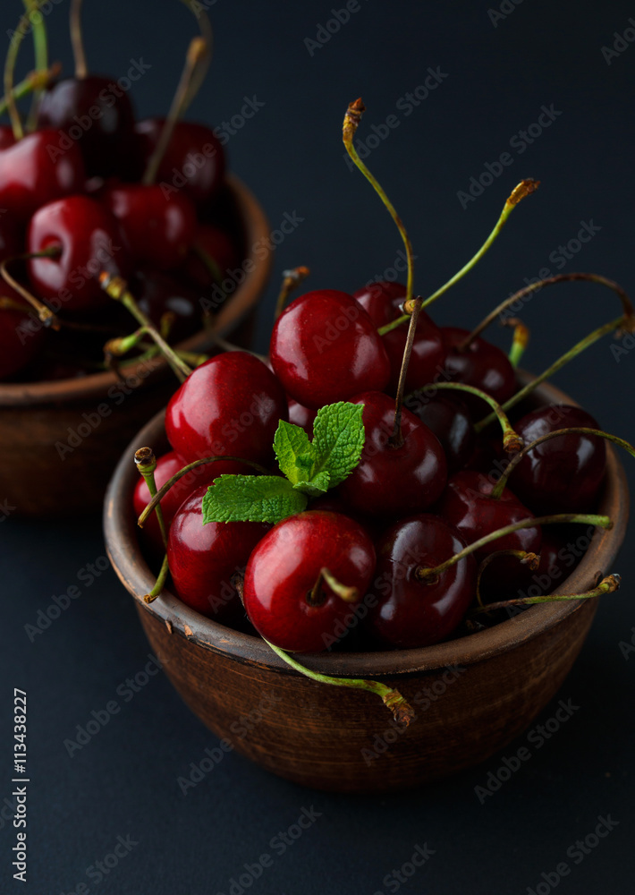 Ripe cherries in a clay bowl on black background Ripe cherries in a clay bowl on black background