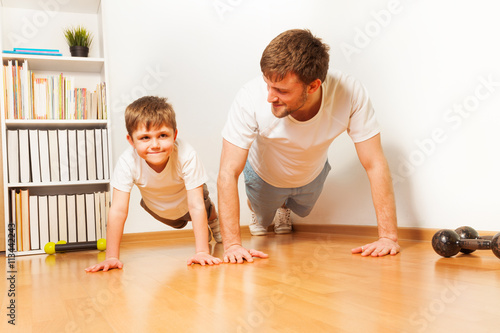 Father teaching kid son doing push-ups exercises