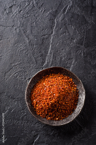 Long black pepper in metal bowl on dark stone background. Selective focus. Top view. Background with place for text