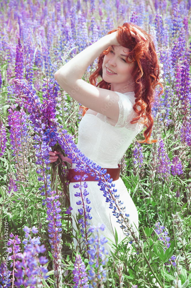 Redhead woman with long hair in lupine field Redhead woman with long hair in lupine field