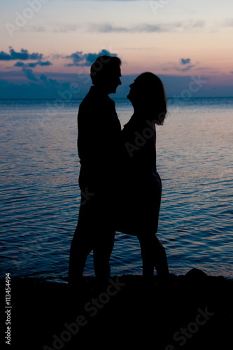 silhouette of two people near the sea