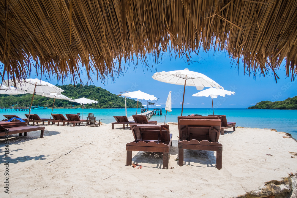 Beach chairs and white umbrella on the tropical beach