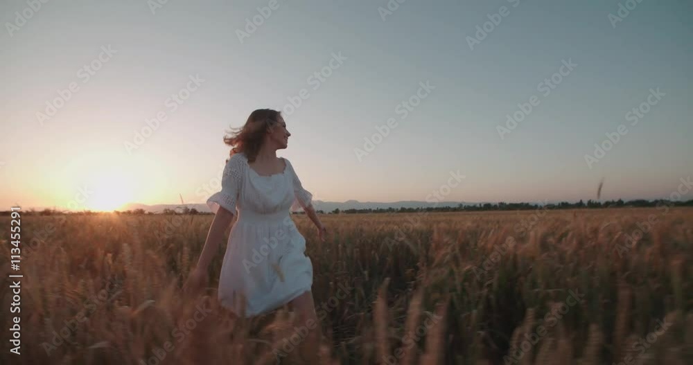 Beauty girl running on yellow wheat field. Freedom concept. Happy woman outdoors. Harvest. Wheat field in sunset