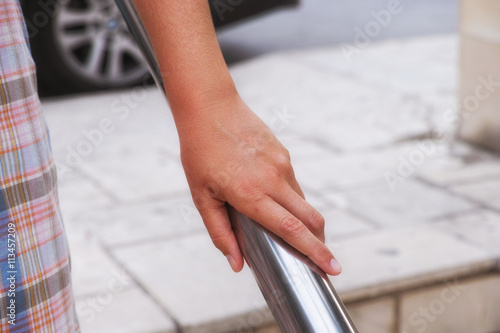 Woman hand using handrail. Urban scene.