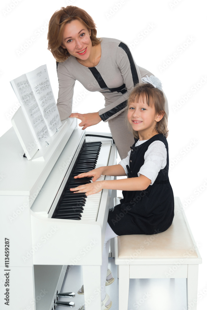 Fototapeta Pilna dziewczynka gra na pianinie pod kierunkiem nauczyciela - na białym tle