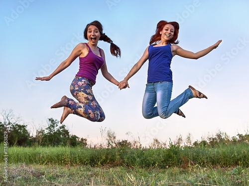 Two girls jumping in the air holding hands