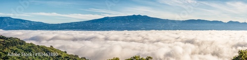 Fototapeta Naklejka Na Ścianę i Meble -  Barva volcano and near mountain ranges in the central valley of Costa Rica seen above the clouds that completly cover the city of San Jose the during the morning