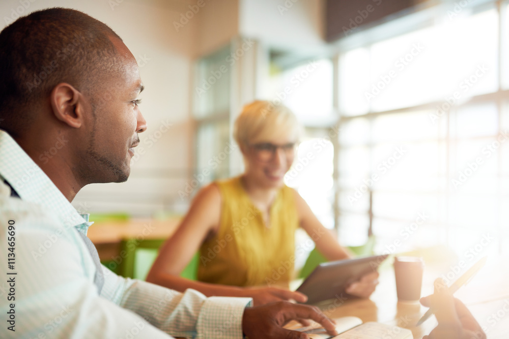 Fototapeta premium Two creative millenial small business owners working on social media strategy using a digital tablet while sitting at desk