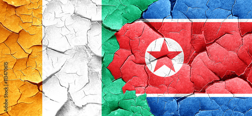 Ivory coast flag with North Korea flag on a grunge cracked wall