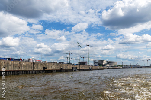 quay of a port with cranes and construction sites  cloudy blue sky