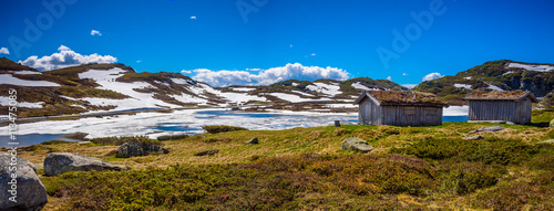 Panorama with melting snow and small cabins in Norway