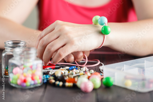 Womanâ€™s hands making bracelete with plastic beads
