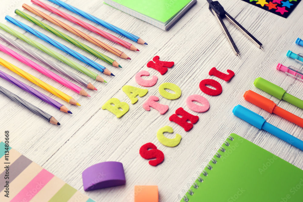 School set with back to school inscription, notebooks on light wooden background School set with back to school inscription, notebooks on light wooden background