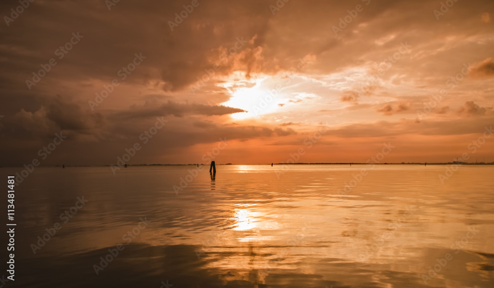 Blazing and vibrant orange summer sunset over Venice lagoon