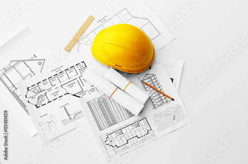 Yellow helmet on the table with blueprints