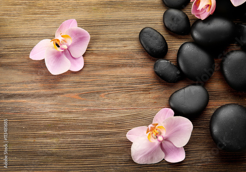 Spa stones and orchid flowers on wooden background