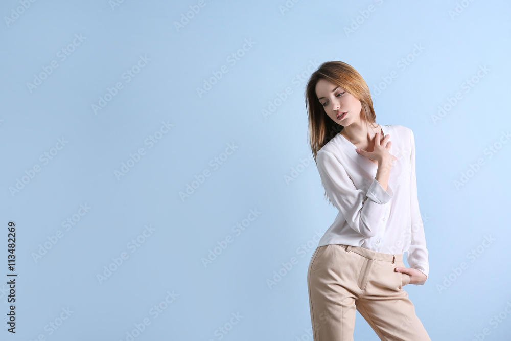 Beautiful young woman in a white shirt and beige pants on blue wall background Beautiful young woman in a white shirt and beige pants on blue wall background