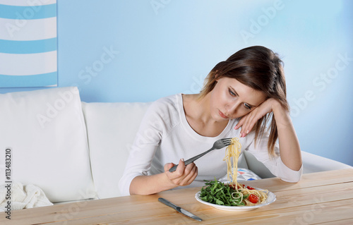 Young depressed girl with eating disorder at wooden table photo