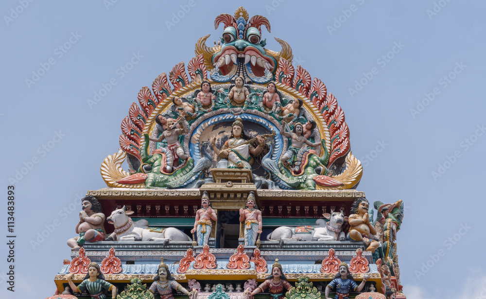 Obraz premium Chettinad, India - October 17, 2013:Detail of the Shiva temple gopuram at Kottaiyur shows Devi Saraswati playing the Veena with dancers and singers. Plenty of colorful statues.