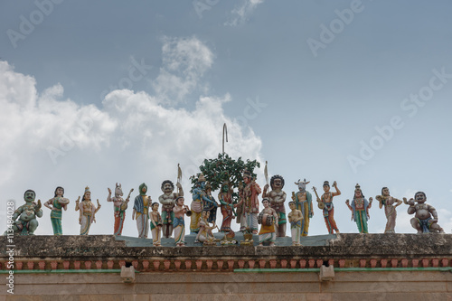 Chettinad, India - October 17, 2013: Row of statues shows the wedding of Shiva with Meenakshi and plenty of guests such as Vishnu, Ayyanar and Hayagriva. Against blue sky. photo