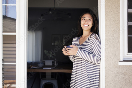 Smiling young woman standing on doorway